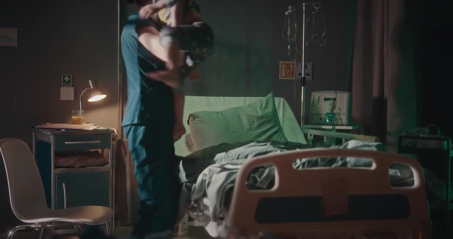 Nurse lifting a young patient and helping him sit up in the hospital bed