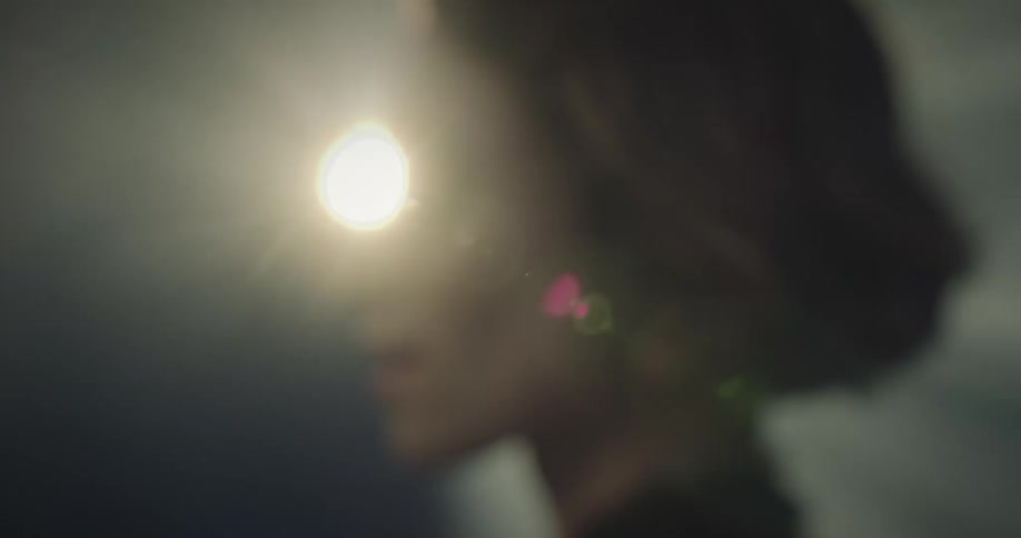 A woman faces sideways while a projector light scans over her face