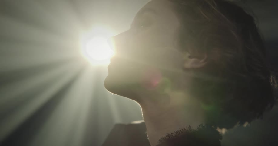 Portrait of a woman with a happy facial expression and lights reflecting on her face in an indoor setting