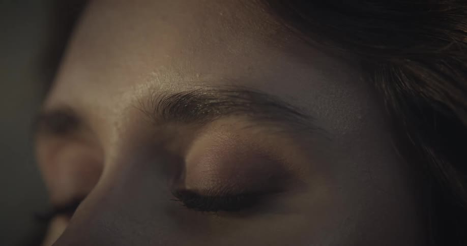 A female face with eyes closed and lights passing through her skin