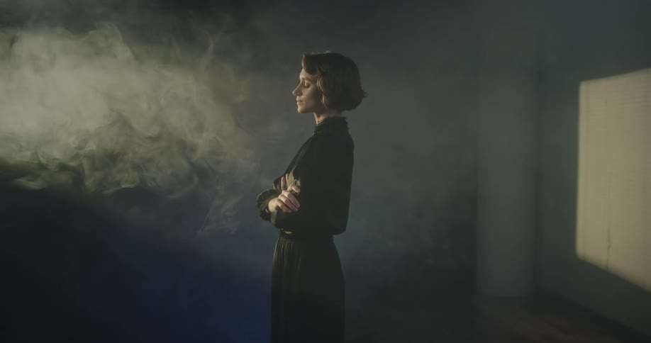 Woman inside a room with smoke and lights wearing a calm facial expression