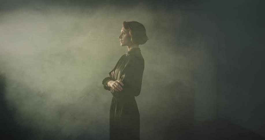 A woman in a dark room illuminated by window light