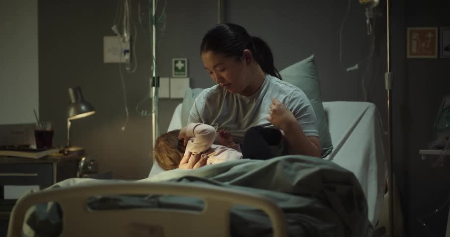 A woman sitting up on a hospital bed holding a baby
