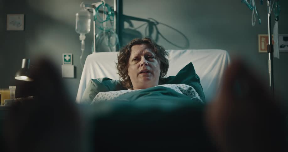 View of the feet of a female patient lying in bed in a hospital room talking to a doctor by her side