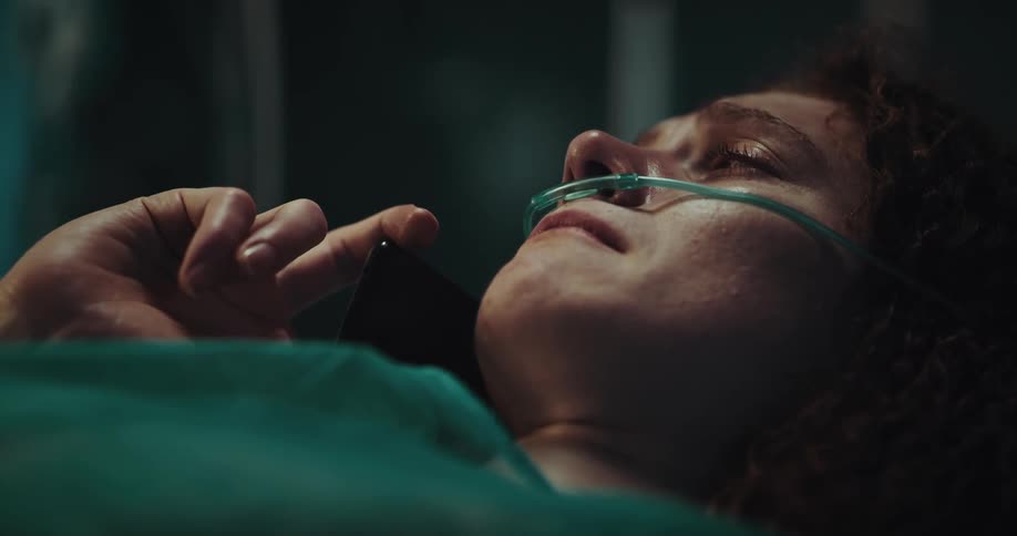 Sad woman lying in a hospital bed crying while talking