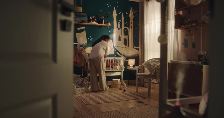 Mother putting her baby daughter in the crib