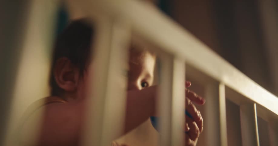 Portrait of a baby inside the crib playing with a blue ball