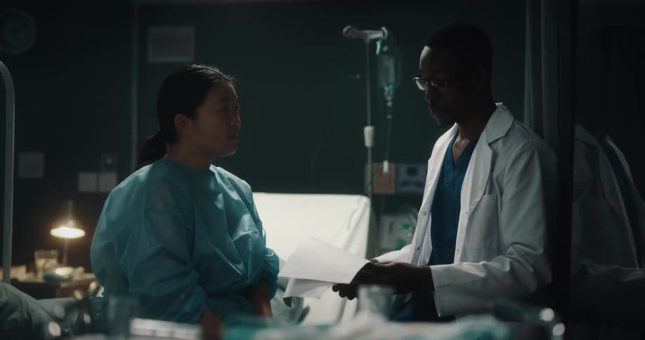 Doctor and a patient conversing with smiles while the doctor flips through a medical chart