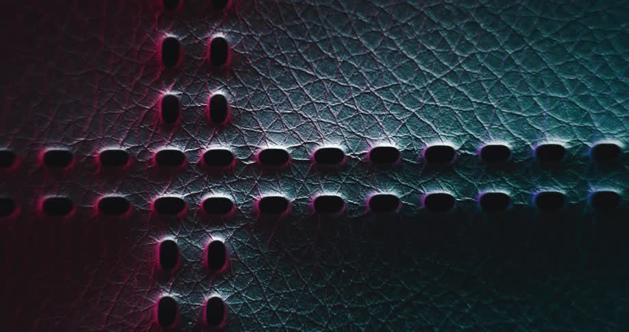 Extreme closeup of a leather mesh with holes and reflections of neon lights