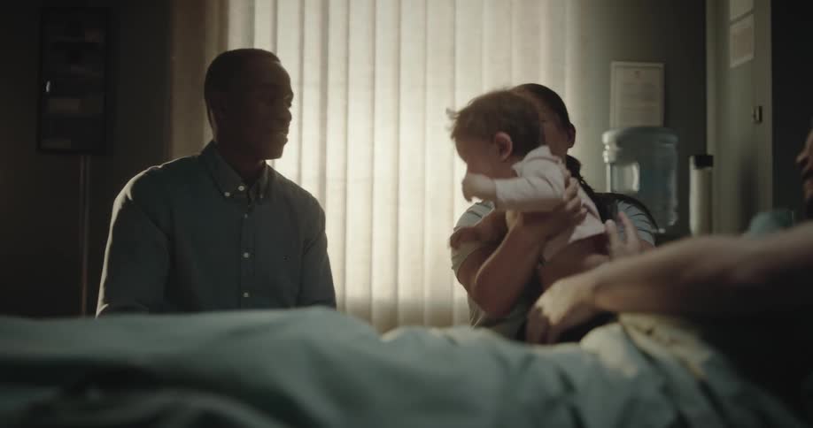 A baby is handed to a man in the hospital