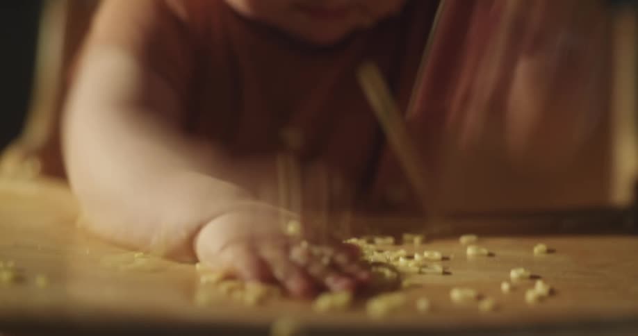 A baby is playing with rice that is mirrored on a table