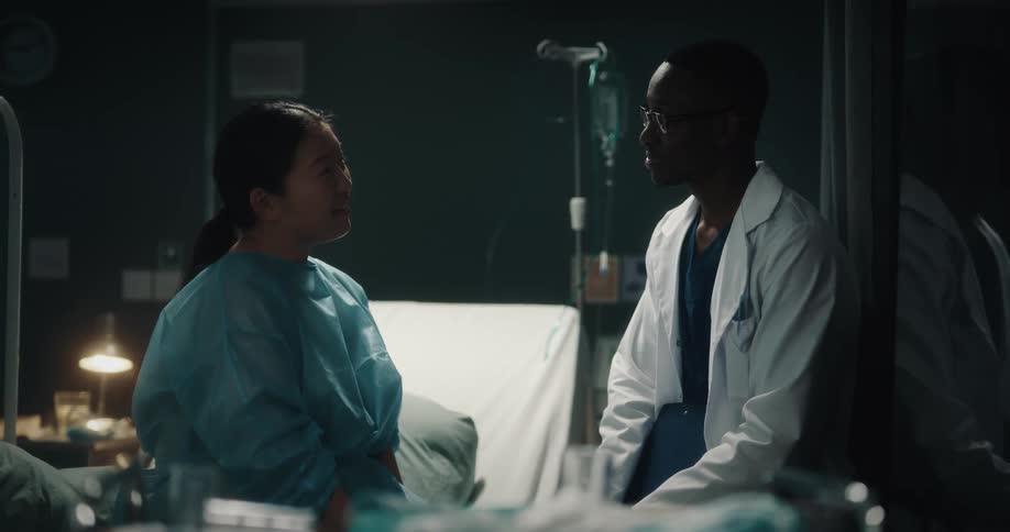Patient sits on hospital bed while talking to doctor