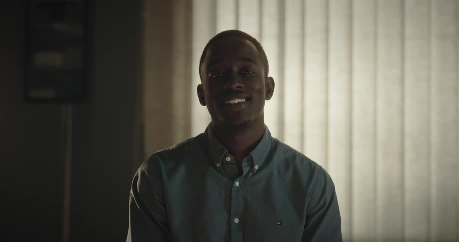 Young man smiles while standing in front of window