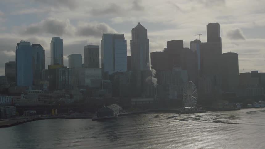 A city skyline by a body of water on a cloudy day