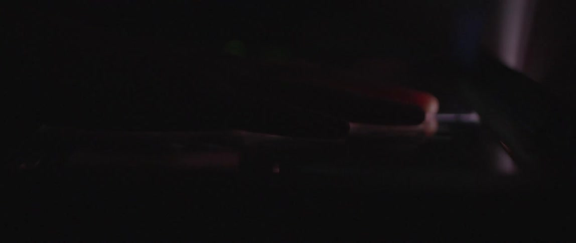 A human hand rising from a completely dark surface and making a small light