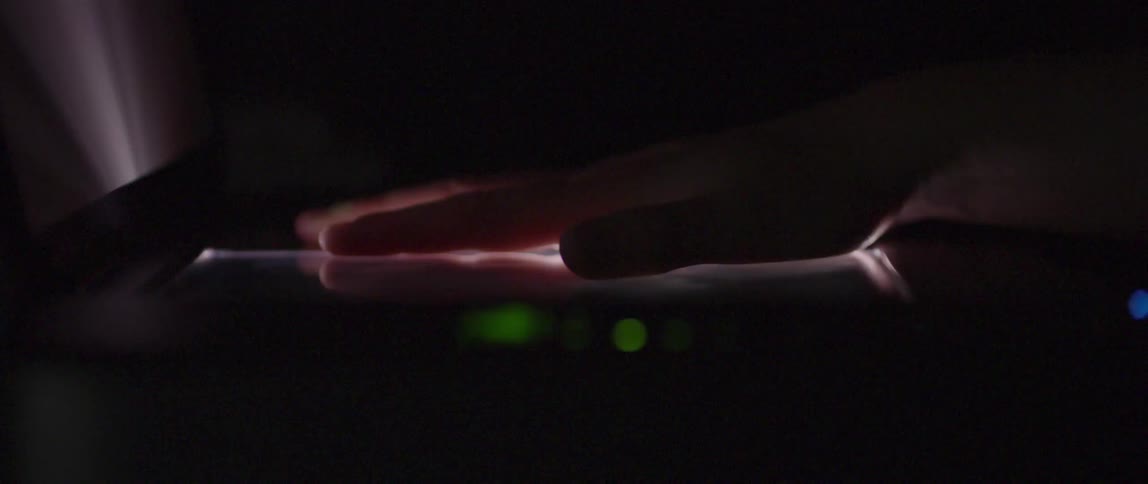 Closeup of a hand on a machine that passes a scanner with a beam of light