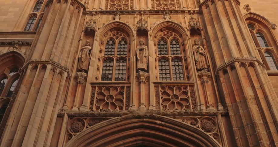 A large stone building is lined with statues
