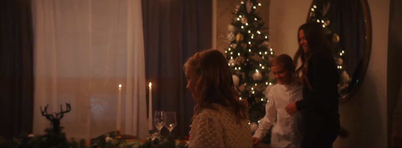 Girl opening the door of the house and greeting family members preparing to sit down for a christmas dinner in the evening