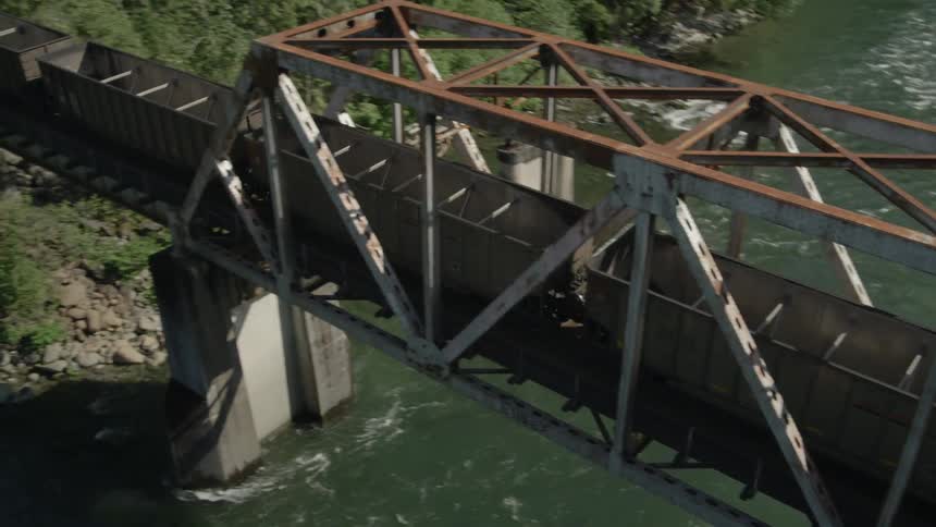 Empty coal train crossing a river bridge