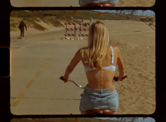 Woman riding a bicycle on the sidewalk next to a beach