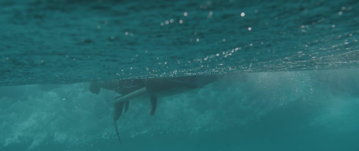 Man riding a wave lying on top of his surfboard