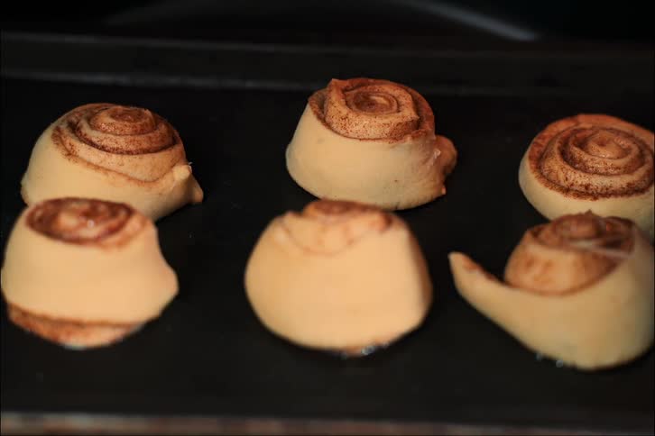 Six cinnamon rolls on a tray in the oven