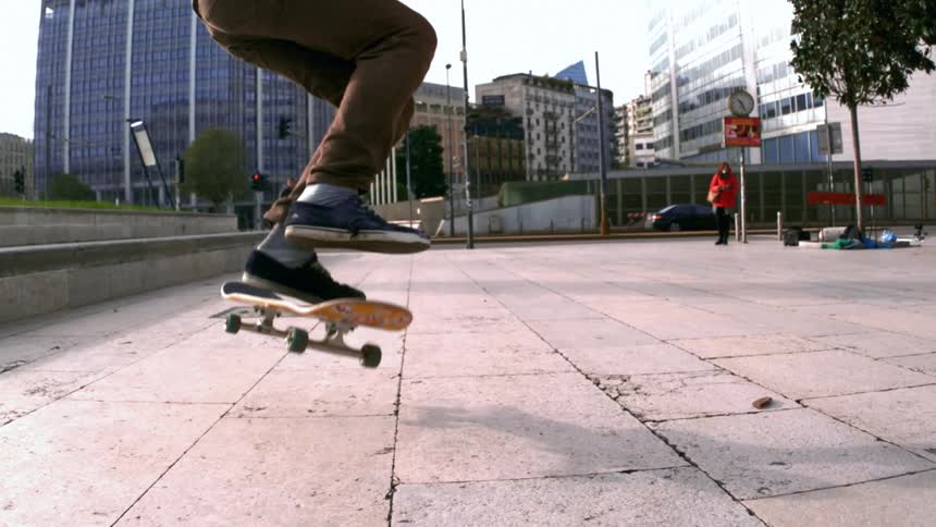 Man performs a skateboard stunt on a pavement at midday
