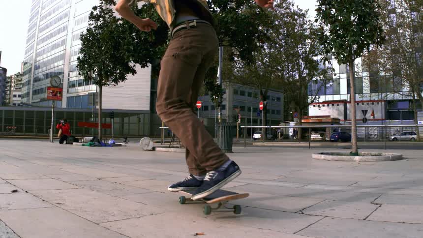 Skateboarder flips board on concreate near trees