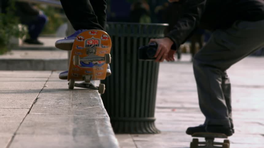 Skateboarder performs jump trick on raised platform while friend records with camera