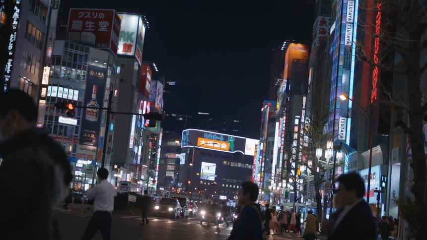 View of a street in tokyo japan where people are crossing the road at night