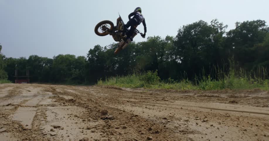Person jumping with their motocross bike on a natural track