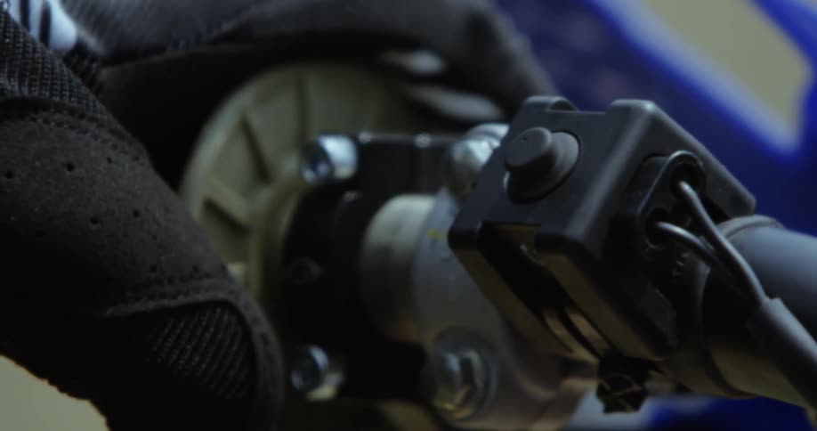 Gloved hand operates motocross presses starter button