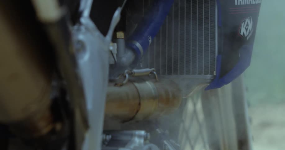 A motocross is bringing out smokes from the engine while its still running