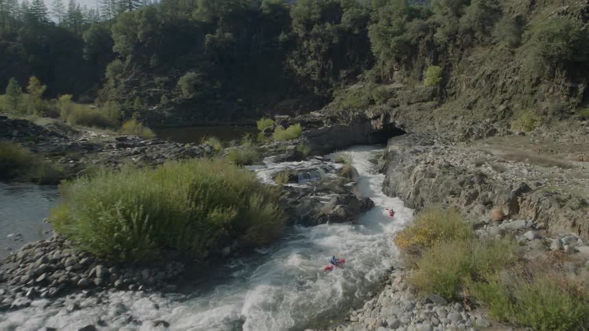 Two paddlers kayaking through fast river rapids