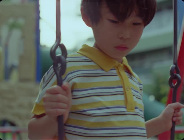 Boy sitting on a swing with a sad facial expression