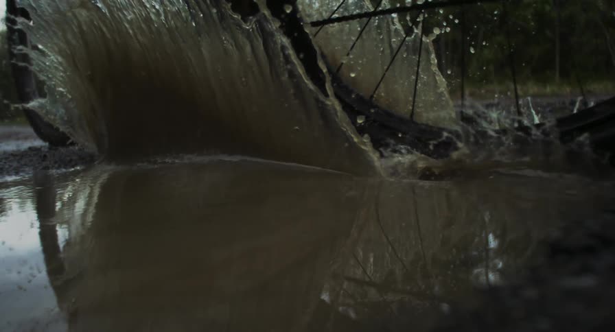 Bicycle wheel passing through a puddle of water in the midst of nature