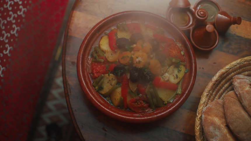 Closeup of hands removing the lid from a bowl and presenting a dish