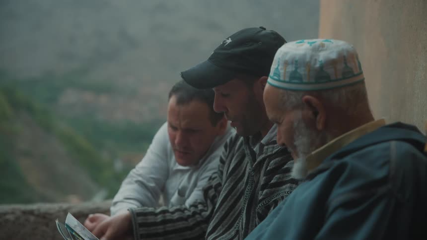 Three men sitting and looking at photos