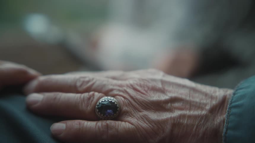 Closeup of the hands of an elderly person with a ring featuring a precious stone