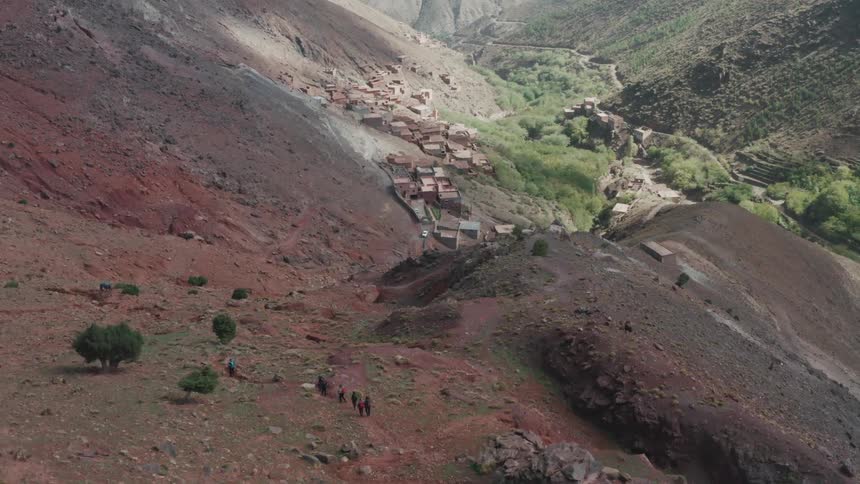 People walking in the mountains with a village below