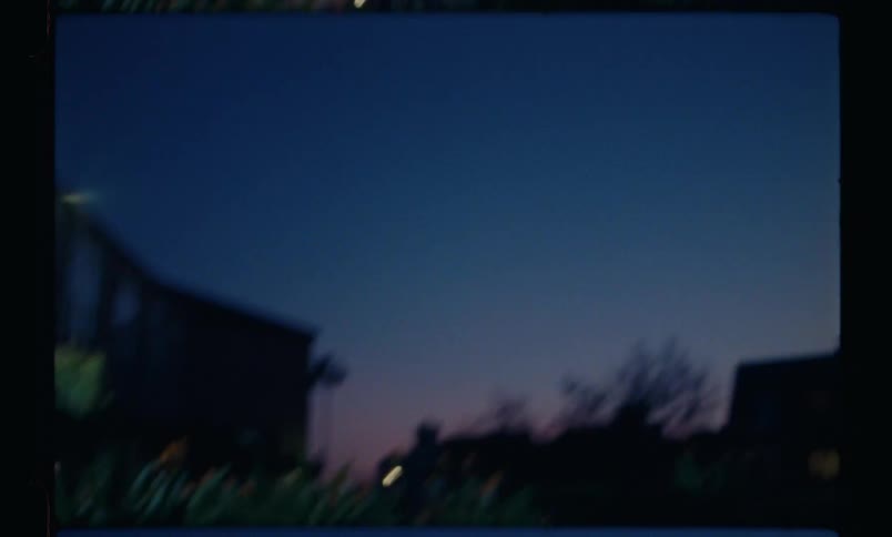 Woman placing her hands on the grass and lifting her feet up in a garden during the night