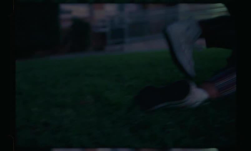Three teenage girls are playing jumping over each other on a lawn in front of a house