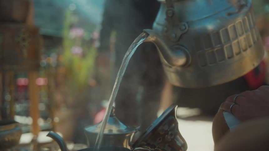 Person holding a kettle with boiling water and pouring it into a container