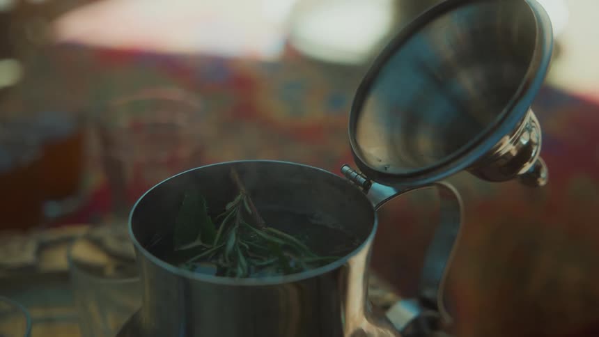 Man adds herbs and sugar to hotwater in teapot