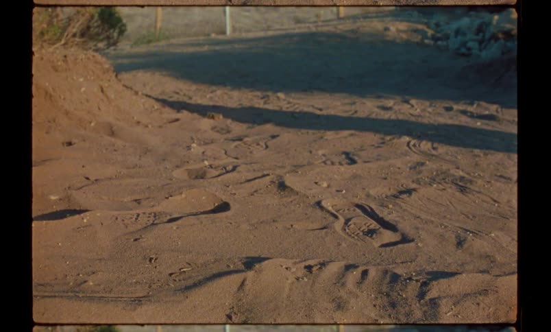 Person standing on sandy ground walks away