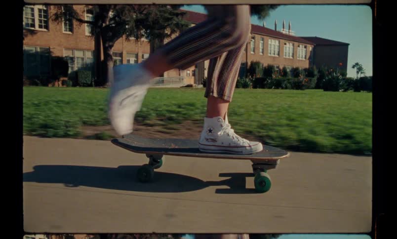 Female legs on a skateboard on the sidewalk at sunset