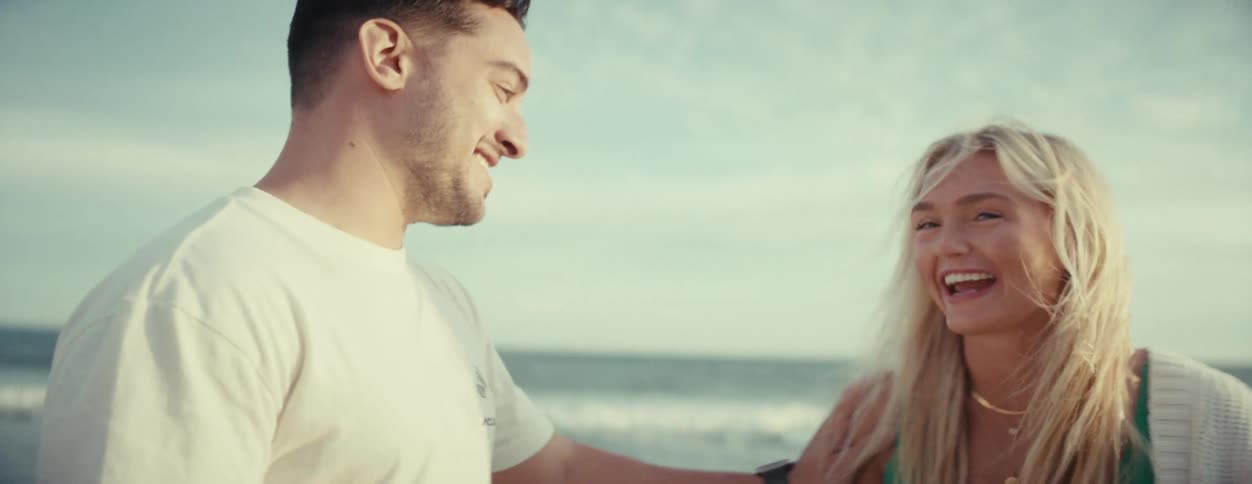 Couple looking at each other and smiling on the beach sand