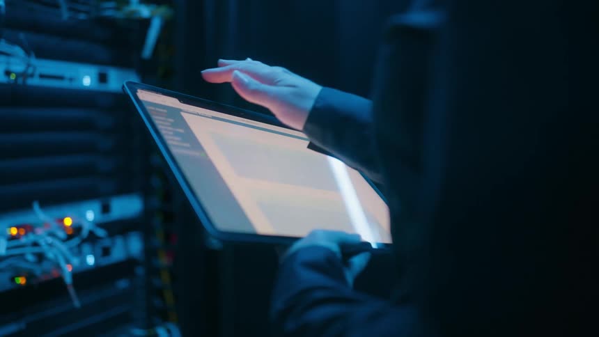Person holding a tablet inside a hardware and network room