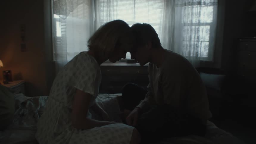 Man and woman locked their foreheads together while seated on the bed indoor
