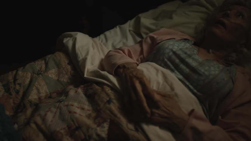 An elderly woman lies in bed peacefully at rest